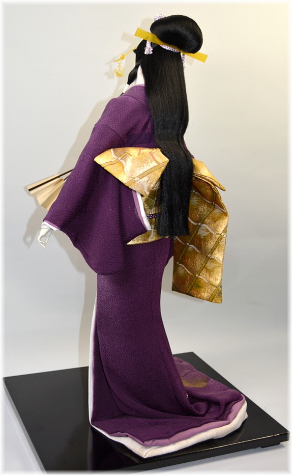 japanese traditional doll of a young woman dancing with folding fan in her hand